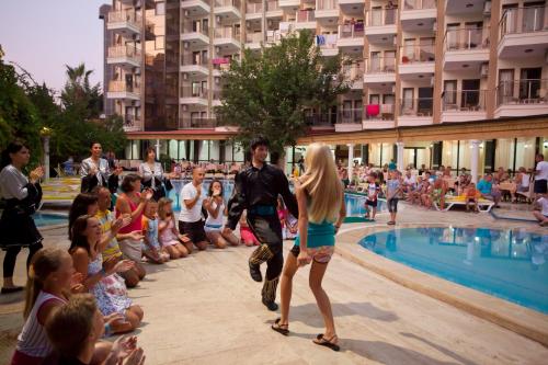 a group of people standing around a swimming pool at Monte Carlo Hotel in Alanya