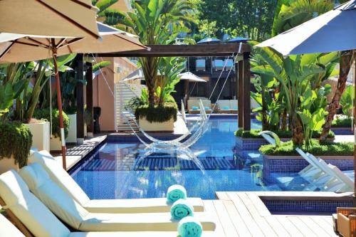 a swimming pool with chairs and umbrellas at Iberostar Selection Jardín del Sol Suites - Adults Only in Santa Ponsa