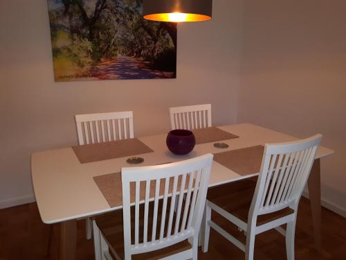 a white table with four chairs and a painting on the wall at Charmant und stilvoll in Kaarst