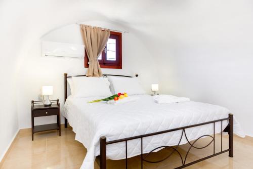 a bedroom with a white bed with flowers on it at Aspalathos Suites in Akrotiri