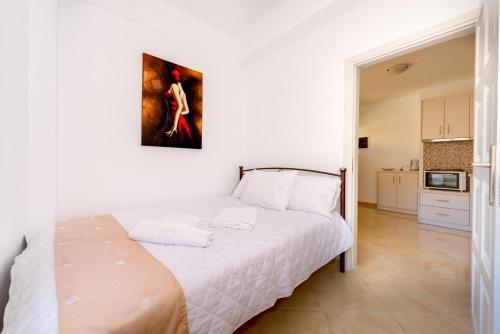 a bedroom with a white bed with a painting on the wall at Aspalathos Suites in Akrotiri