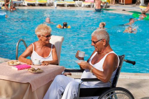 two older women sitting at a table by a pool at Monte Carlo Hotel in Alanya