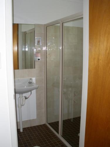 a bathroom with a shower and a sink at Palms Oasis Motel in Coopernook