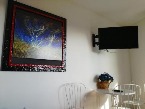 a painting hanging on a wall with a table and chairs at Cominium Benessere in Alvito