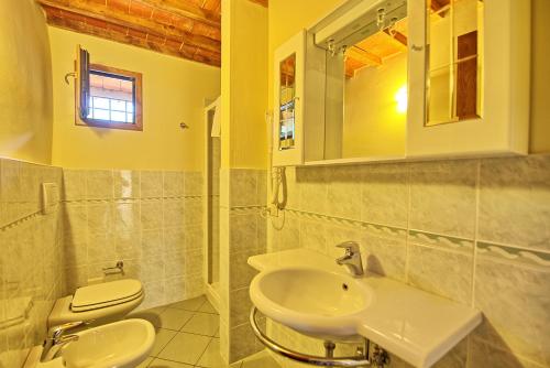 a bathroom with a sink and a toilet and a mirror at Villa Poggio Conca by PosarelliVillas in Incisa in Valdarno