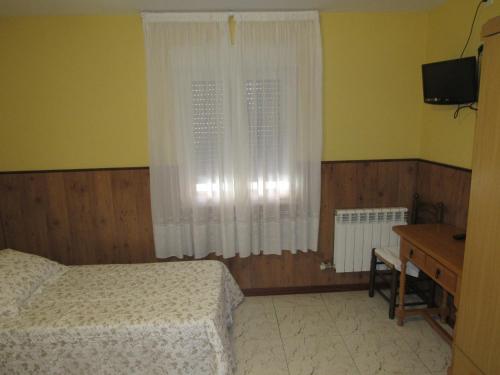 a bedroom with a bed and a window and a desk at Hostal Restaurante El Abuelo in Trobajo del Camino