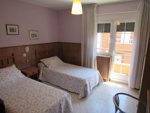 a hotel room with two beds and a window at Hostal Restaurante El Abuelo in Trobajo del Camino