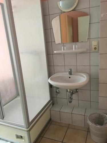 ein Bad mit einem Waschbecken und einem Spiegel in der Unterkunft Hotel Yans in Oberhausen