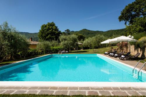 a blue swimming pool with chairs and umbrellas at Casa Vacanze Villa il Castellaccio in Lucolena in Chianti