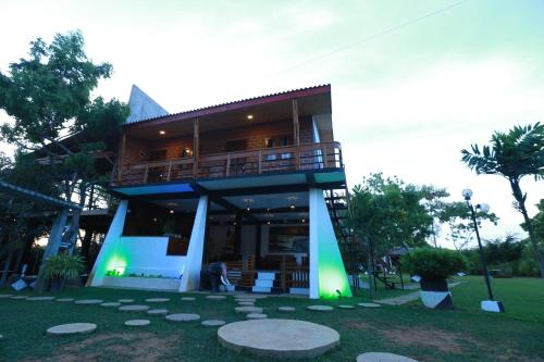 a house with a deck and a staircase in a yard at Eco Hotel Black & White - Anuradhapura in Mihintale