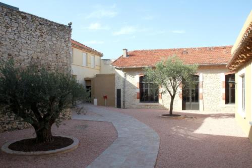 une cour avec deux arbres et un bâtiment dans l'établissement Logis Hotel Le Clos Des Oliviers, à Bourg-Saint-Andéol