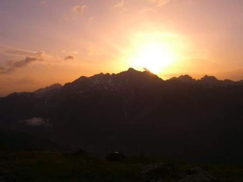 a sunset over a mountain with the sun setting at Haus Talblick in Pettneu am Arlberg