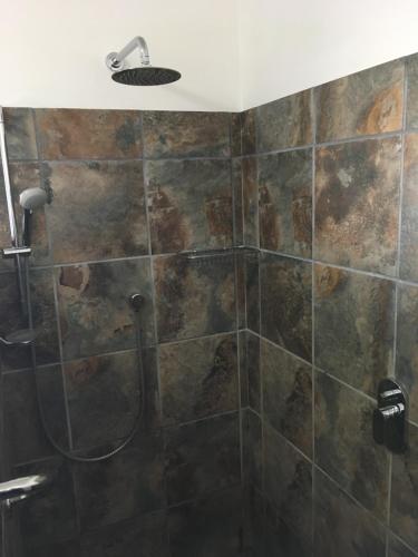 a bathroom with a shower with a stone wall at van Biljon Cottage No Loadshedding in Oudtshoorn