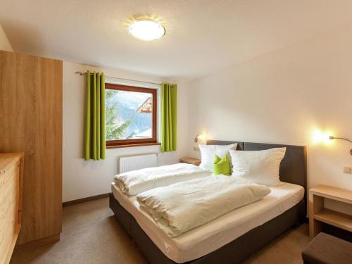 a bedroom with a large bed with green curtains at Haus Talblick in Pettneu am Arlberg