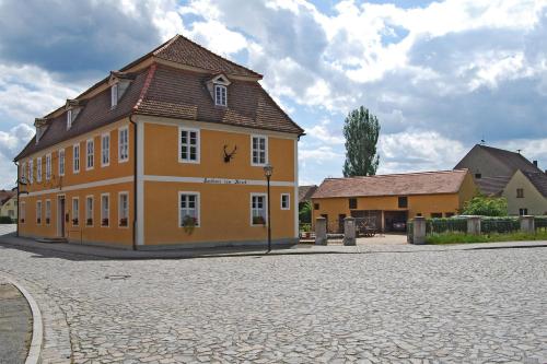 a yellow building with a brown roof on a street at Gasthof Zum Hirsch in Drehna