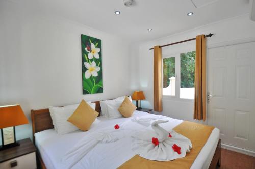 Un dormitorio con una cama blanca con dos cisnes. en Yasad Residence, en Anse Possession