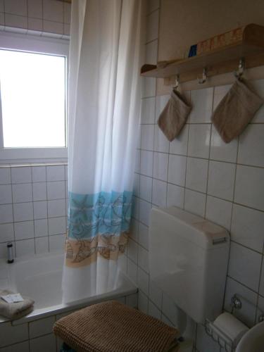 a bathroom with a tub and a toilet and a window at Haus Steinbach in Kellenhusen
