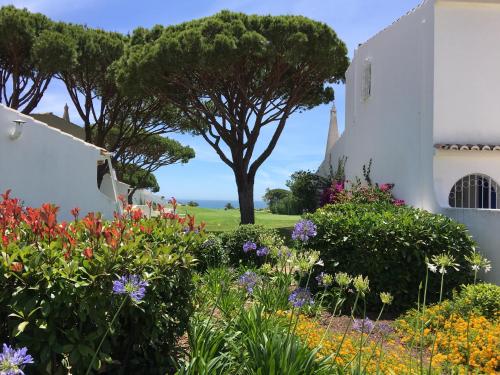 a garden in front of a white building with flowers at Vale Do Lobo 935 in Loulé