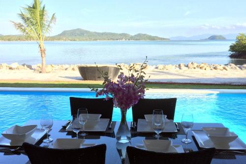 a table with wine glasses and a vase with flowers on a beach at Bliss Villas in Srithanu