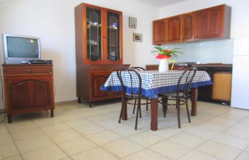 レウカにあるBilocale con spazio verdeのキッチン(テーブル、椅子、テレビ付)