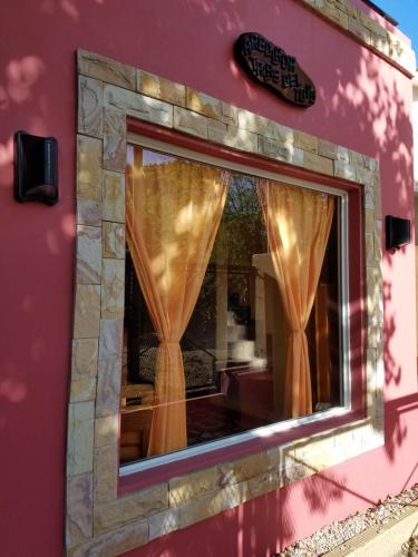 a window on a pink building with curtains at Arbolada Talas del Tuyu in San Clemente del Tuyú