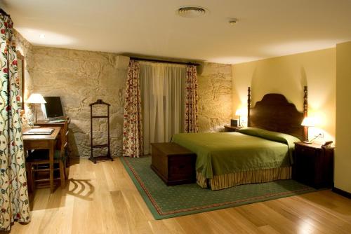 ein Schlafzimmer mit einem Bett, einem Schreibtisch und einem Computer in der Unterkunft Hotel Pazo de Lestrove by Pousadas de Compostela in Padrón