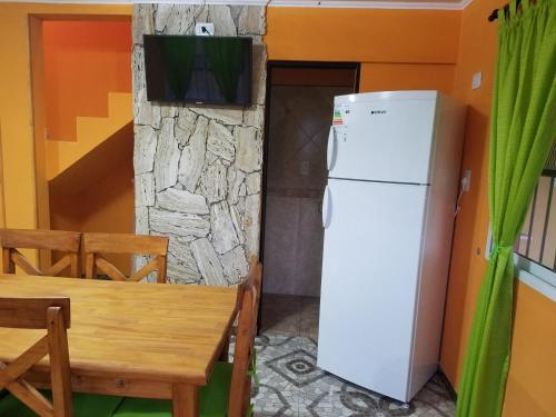 a kitchen with a white refrigerator and a table at Arbolada Talas del Tuyu in San Clemente del Tuyú