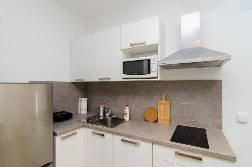 een keuken met witte kasten, een spoelbak en een magnetron bij ABC Lapad Apartments in Dubrovnik