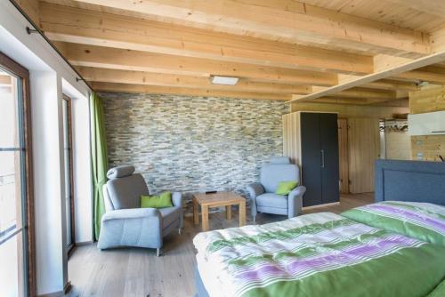 a bedroom with a bed and two chairs and a brick wall at Ferienhaus Albzeit in Albstadt