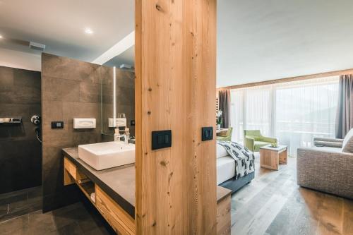 1 dormitorio y baño con lavabo. en Dolasilla Mountain Panoramic Wellness Hotel en La Villa