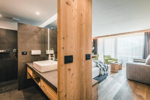 a bathroom with a sink and a bedroom at Dolasilla Mountain Panoramic Wellness Hotel in La Villa