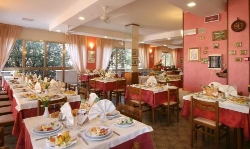 リミニにあるHotel Marselliのテーブルと椅子、食器を用意したレストランを併設しています。