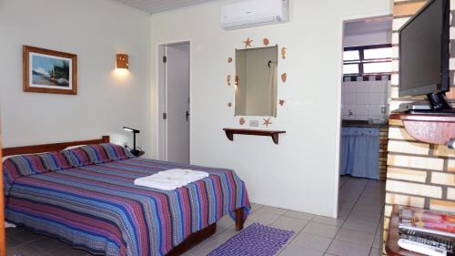 a bedroom with a bed and a mirror and a sink at Pousada Barratur in Florianópolis
