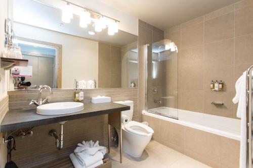 a bathroom with a sink and a toilet and a tub at The Sidney Pier Hotel & Spa in Sidney