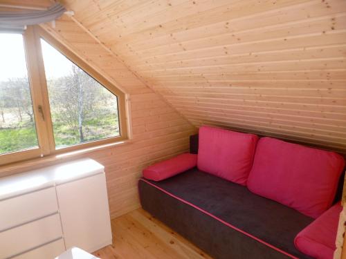 a couch in a tiny house with a window at Cztery Pory Roku in Trzęsacz