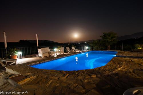 a large blue swimming pool at night at Villafranco Apartamentos in Villafranco de Guadalhorce