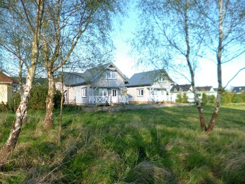 a house in the middle of a field with trees at Cztery Pory Roku in Trzęsacz