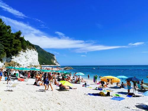 una folla di persone su una spiaggia con ombrelloni di Camere Due Per Due a Sirolo