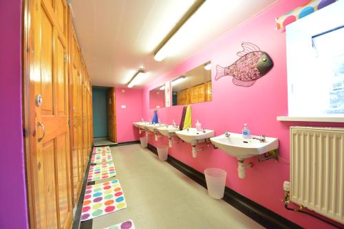 a pink bathroom with sinks and a fish on the wall at Oban Backpackers in Oban