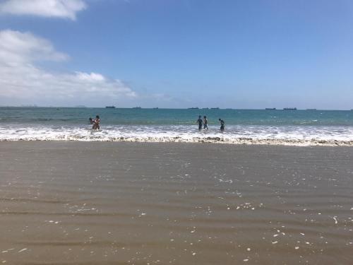a group of people standing in the water at the beach at BlackPoint in Ballenita