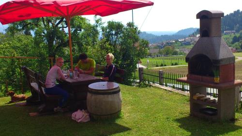a group of people sitting at a table under an umbrella at Apartments and Rooms With View on Bled in Bled
