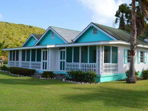 a blue and white house with a palm tree at Oualie Beach Resort in Nevis