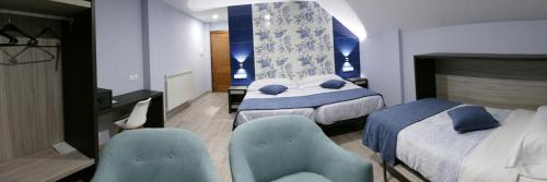 a hotel room with two beds and a desk and chairs at Hotel Rural El Nido de Pinares in Navaleno