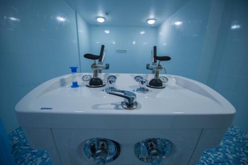 a bathroom with a sink with two faucets and a mirror at Lisova Pisnia Resort Hotel in Truskavets