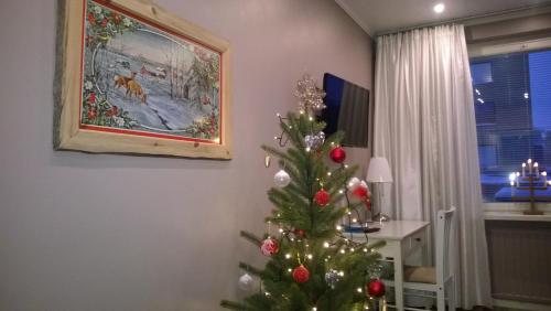 a christmas tree in a living room with a painting at Piriko Studio Apartments in Rovaniemi