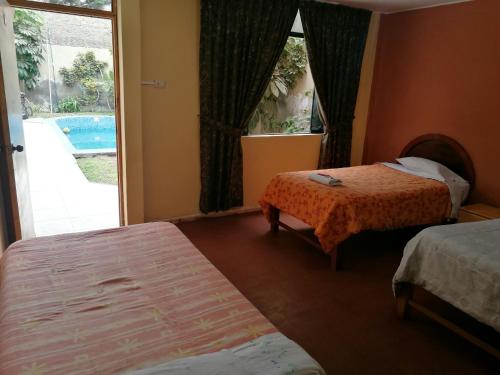 a hotel room with two beds and a window with a pool at Hostal Shalom in Pisco
