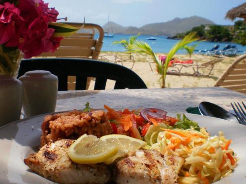a plate of food on a table near the beach at Oualie Beach Resort in Nevis