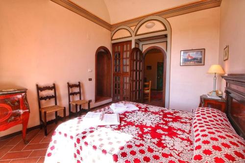 1 Schlafzimmer mit einem roten und weißen Bett mit 2 Stühlen in der Unterkunft App.to Le antiche Poste in Piegaro