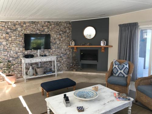 a living room with a fireplace and a tv on a stone wall at Akwa in Hermanus
