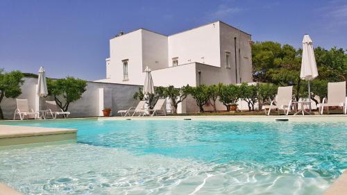 una piscina con sedie e ombrelloni di fronte a un edificio di Casina Bardoscia a Cutrofiano